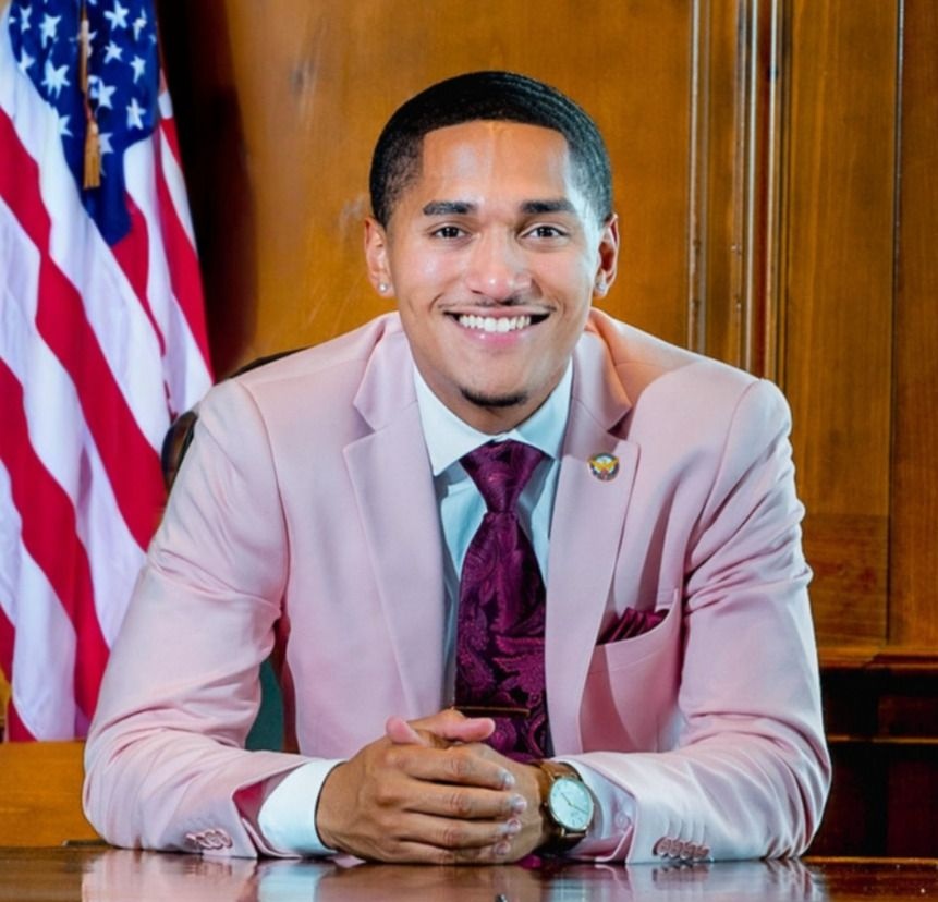 Mikel Caldwell of Alpha Phi Alpha Fraternity, Inc. at Clark Atlanta University, wearing a pink suit and deep purple tie
